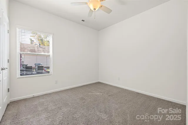 an empty room with a window and a ceiling fan
