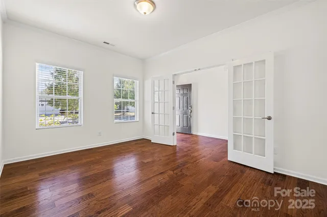 an empty room with wooden floor and windows
