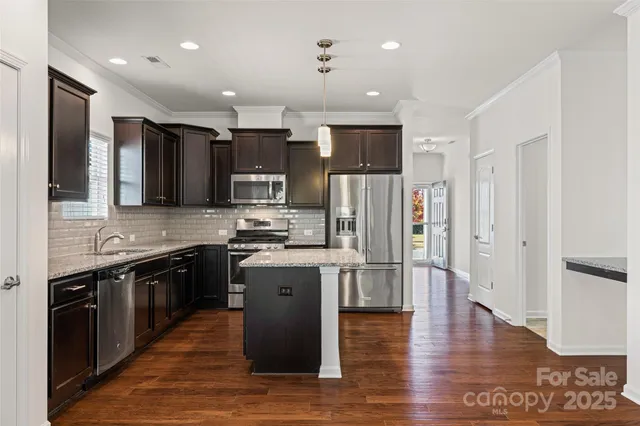 a kitchen with stainless steel appliances granite countertop a refrigerator a stove top oven and sink