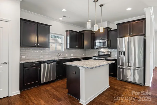 a kitchen with stainless steel appliances granite countertop wooden cabinets a refrigerator a sink and a stove