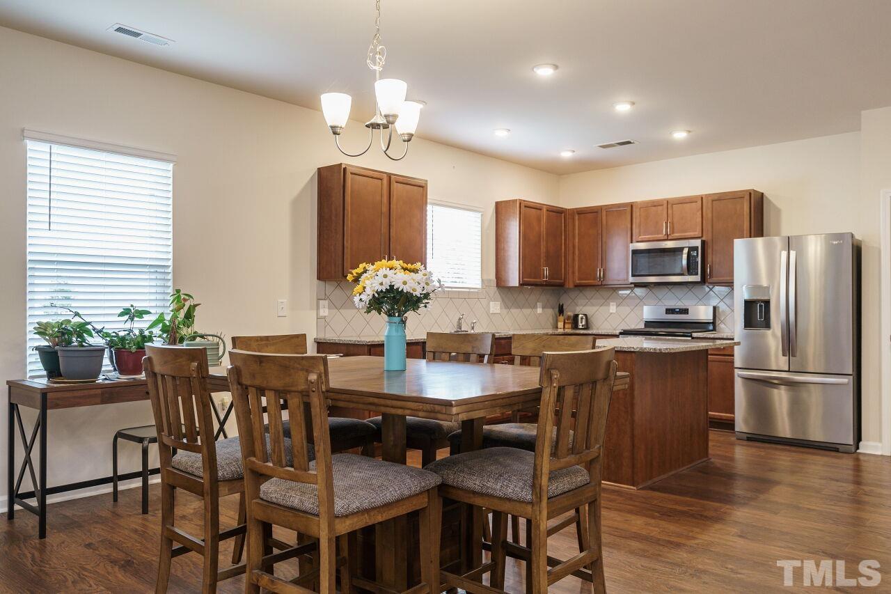 4100 Catfish Wy. Durham, NC 27703 - Photo 12 of 29 a kitchen with granite countertop stainless steel appliances a dining table and chairs