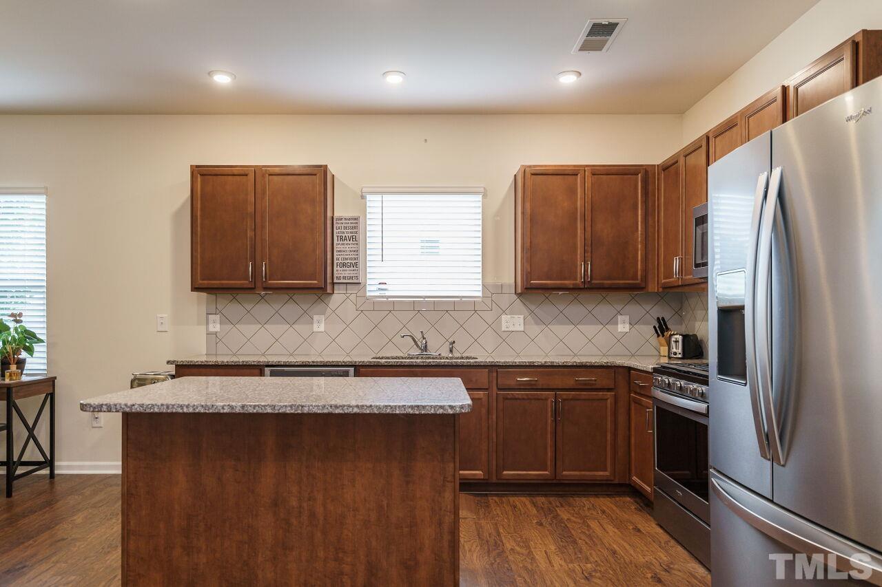 4100 Catfish Wy. Durham, NC 27703 - Photo 9 of 29 a kitchen with stainless steel appliances granite countertop a refrigerator a sink a stove a microwave and island