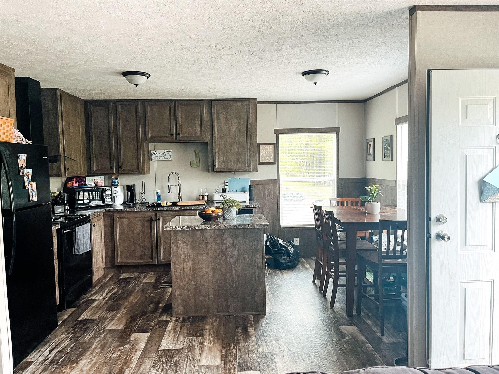 100 Sellers Road Sylva, NC 28779 - Photo 13 of 32 a kitchen with granite countertop a refrigerator a stove top oven a dining table and chairs with wooden floor