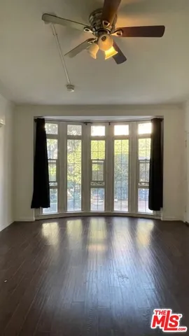 a view of an empty room with window and wooden floor