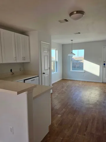 a view of a kitchen with a sink and dishwasher stove top oven with wooden floor