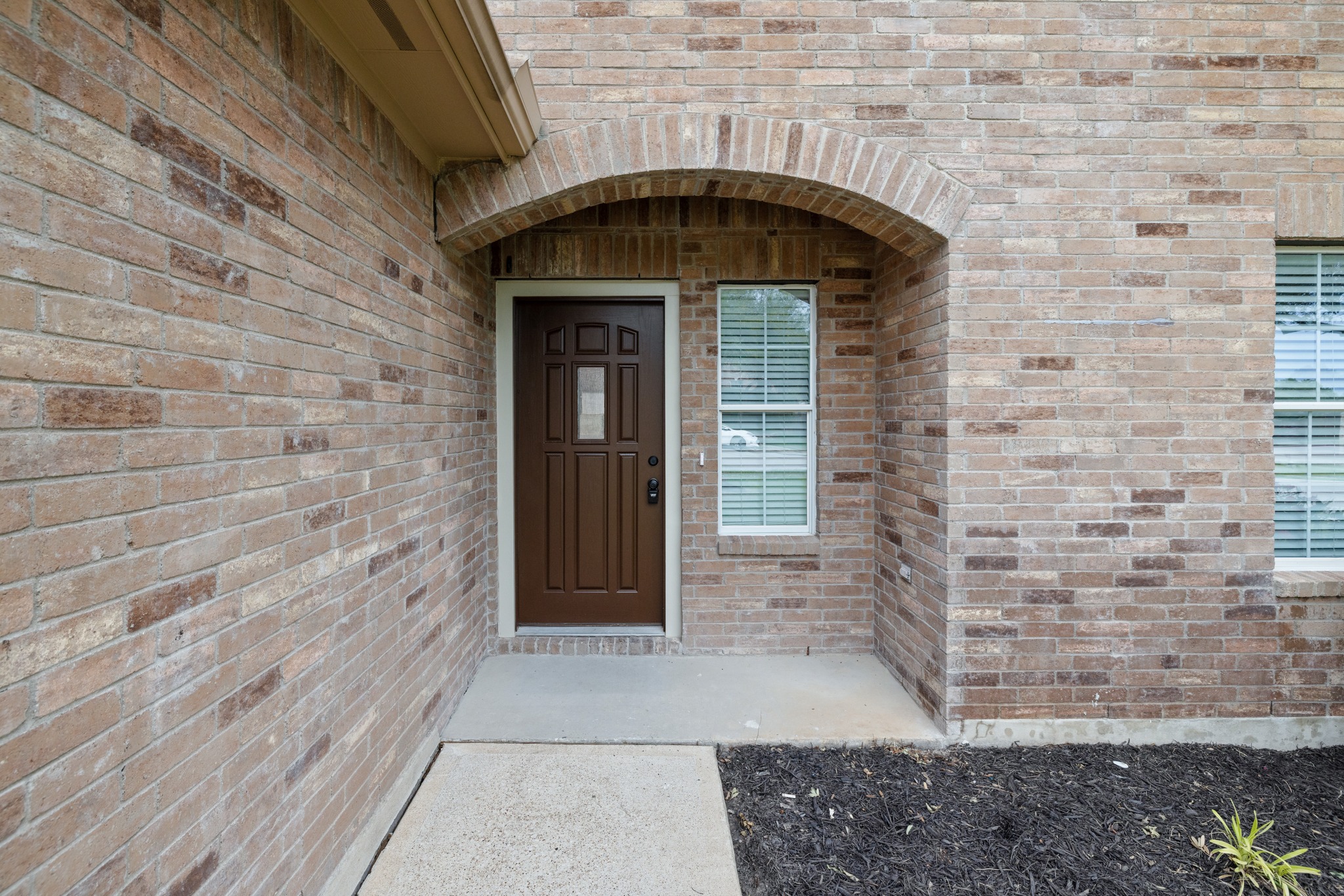 403 Red Hawk Drive Leander, TX 78641 - Photo 3 of 37 Brick exterior with an arched entryway over a paneled front door featuring decorative glass