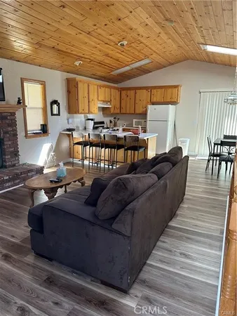 a living room with furniture kitchen view and a wooden floor