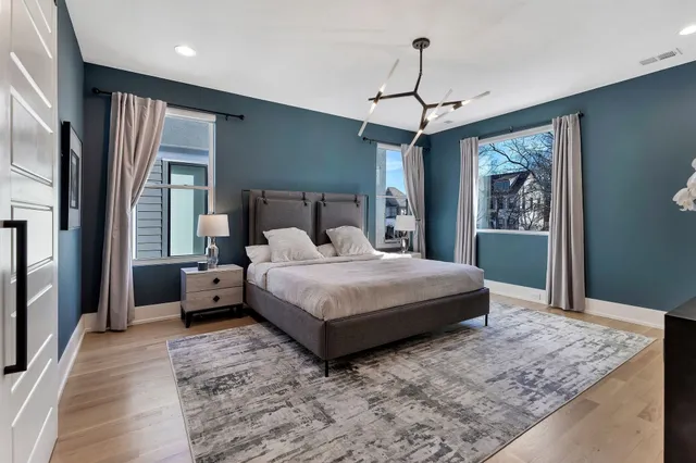 a bedroom with a large bed chandelier and a window
