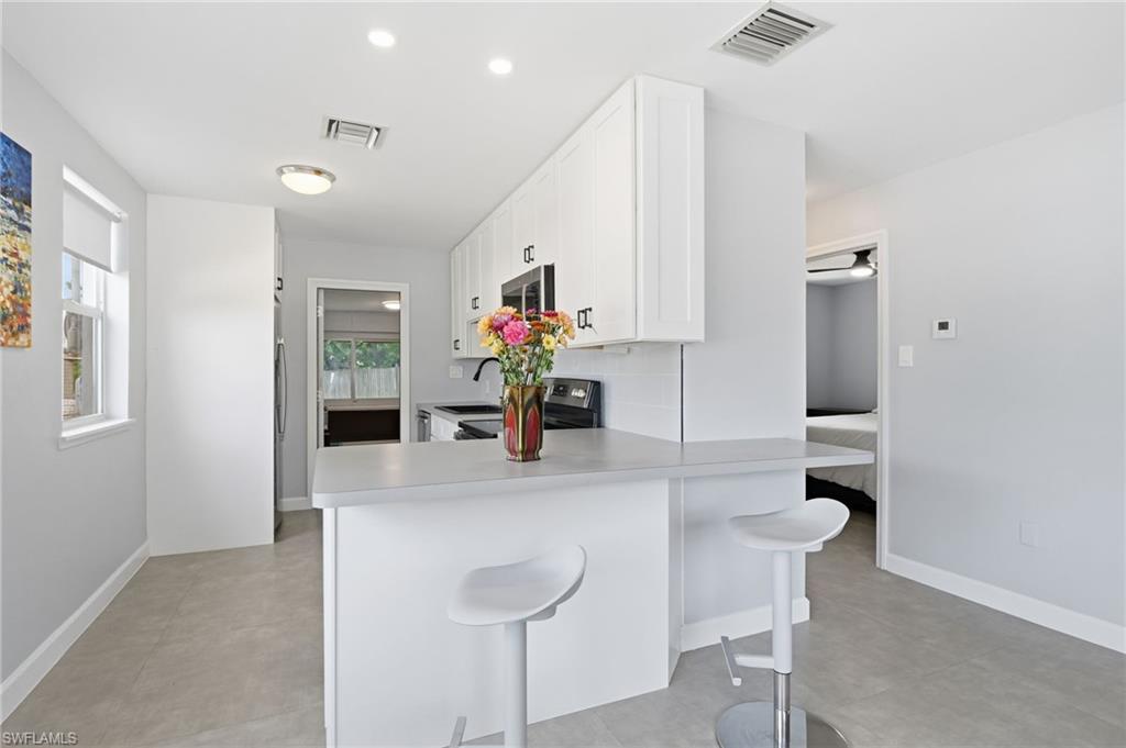 4518 West Alhambra Circle Naples, FL 34103 - Photo 13 of 40 a kitchen with kitchen island a counter top space and a sink