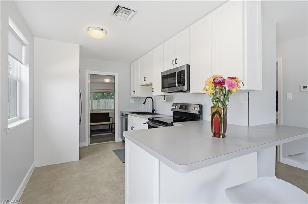 4518 West Alhambra Circle Naples, FL 34103 - Photo 15 of 40 a kitchen with a sink a counter appliances and cabinets