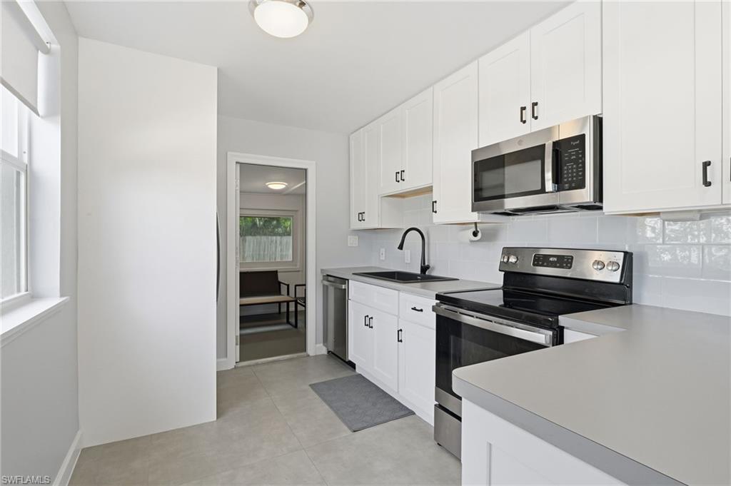 4518 West Alhambra Circle Naples, FL 34103 - Photo 17 of 40 a kitchen with stainless steel appliances granite countertop a stove top oven a sink dishwasher and a refrigerator with wooden cabinets