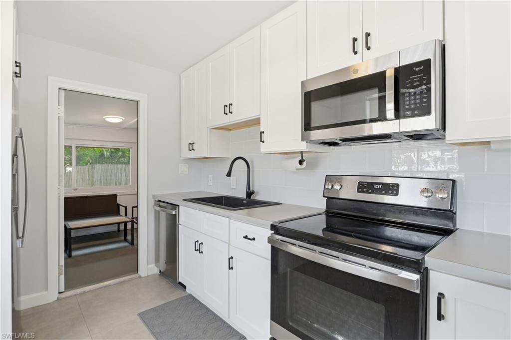 4518 West Alhambra Circle Naples, FL 34103 - Photo 18 of 40 a kitchen with stainless steel appliances a stove microwave and sink
