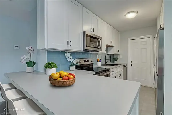 a kitchen with stainless steel appliances a stove a sink a microwave a refrigerator and cabinets