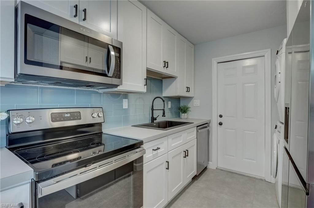 4518 West Alhambra Circle Naples, FL 34103 - Photo 6 of 40 a kitchen with stainless steel appliances granite countertop a stove and a microwave
