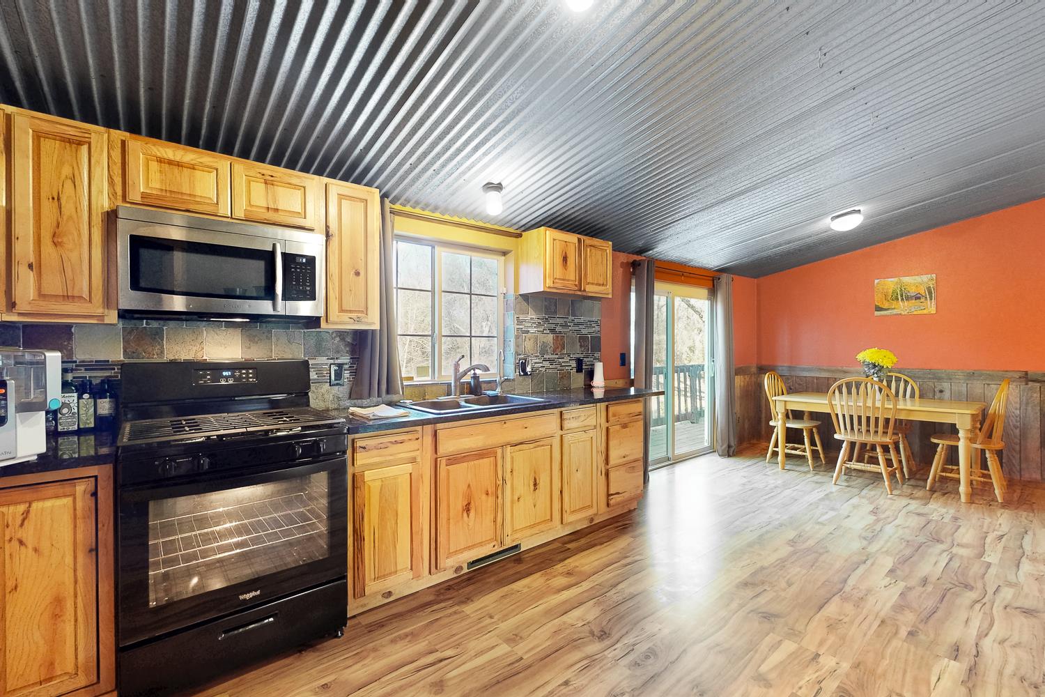 10146 Frenchtown Dobbins Road Dobbins, CA 95935 - Photo 6 of 38 a kitchen with stainless steel appliances granite countertop a stove kitchen island granite countertop a refrigerator a stove a microwave oven with a dining table and chairs with wooden floor