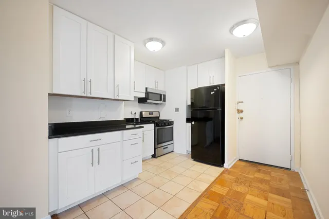 a kitchen with stainless steel appliances granite countertop a stove a microwave and a white cabinets