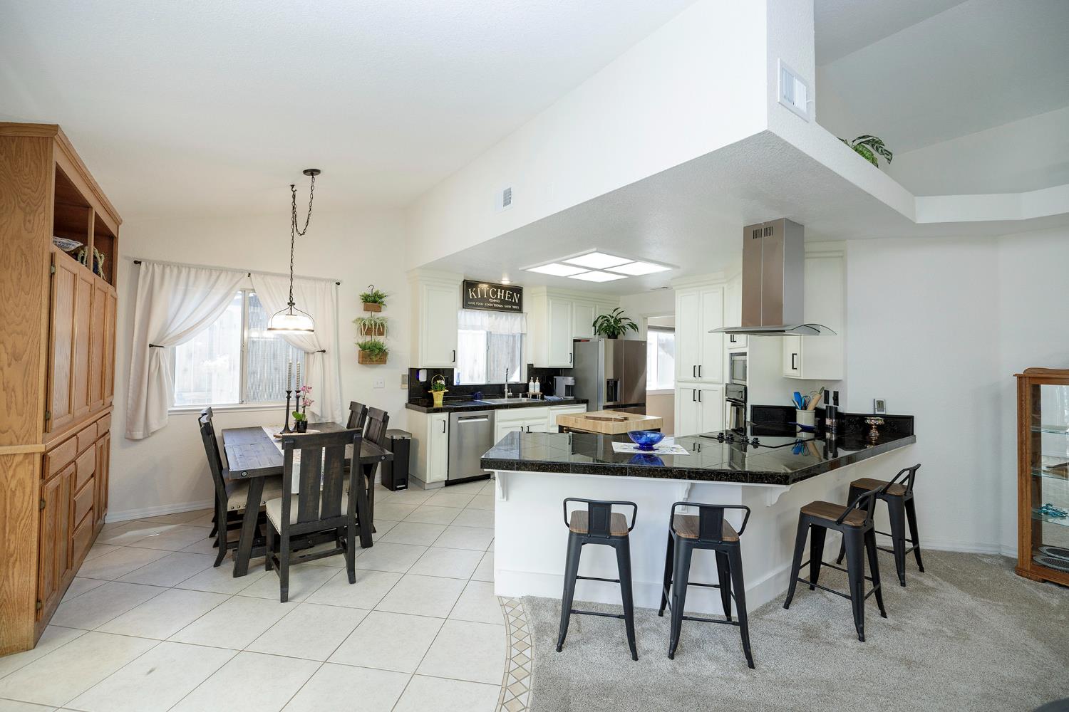 230 Meyenberg Avenue Ripon, CA 95366 - Photo 21 of 52 a kitchen with kitchen island granite countertop a dining table chairs and white cabinets