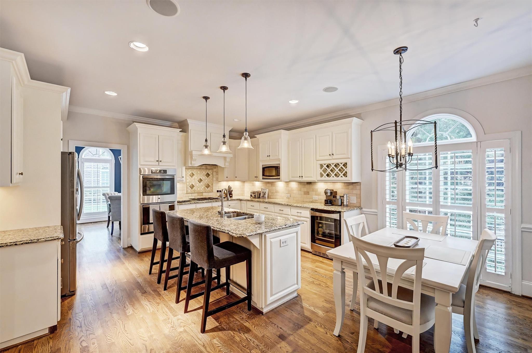 6009 Sharon View Road Charlotte, NC 28226 - Photo 15 of 47 a kitchen with stainless steel appliances kitchen island granite countertop a stove a refrigerator a dining table and chairs with wooden floor