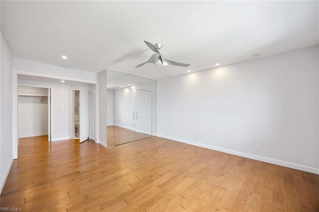 1325 7th Street South, Unit 2B Naples, FL 34102 - Photo 15 of 34 a view of an empty room with wooden floor and a ceiling fan