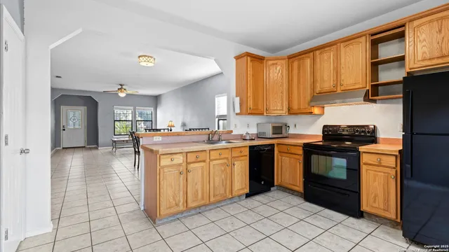 a kitchen with stainless steel appliances granite countertop a stove a sink dishwasher and a refrigerator with wooden cabinets