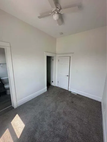 an empty room with a ceiling fan and carpet
