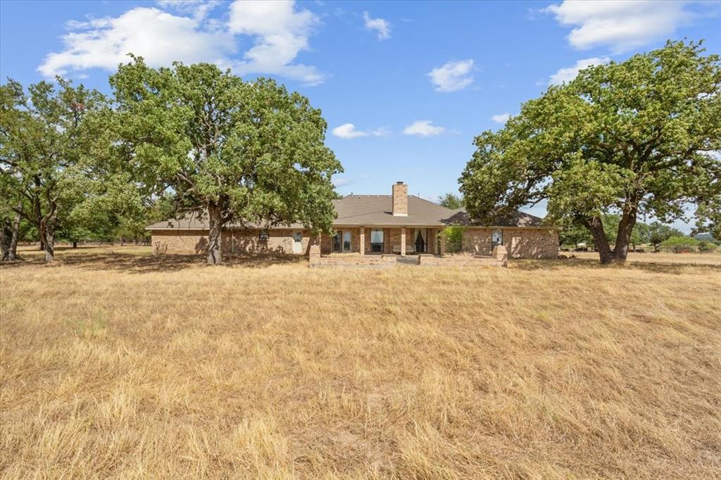410 State School Road Gatesville, TX 76528 - Photo 26 of 39 Single-story brick residence featuring a covered porch, prominent chimney, and a brown shingle roof