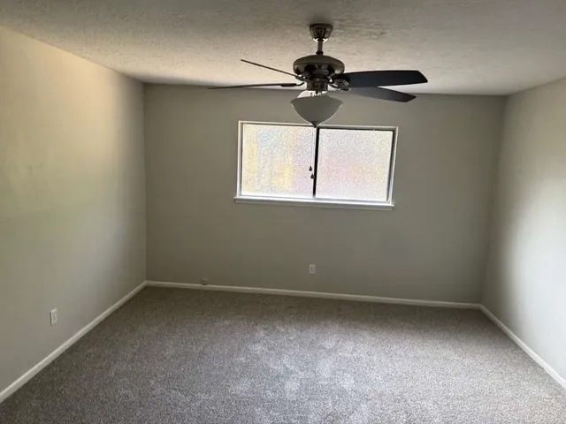 an empty room with a window and a fan