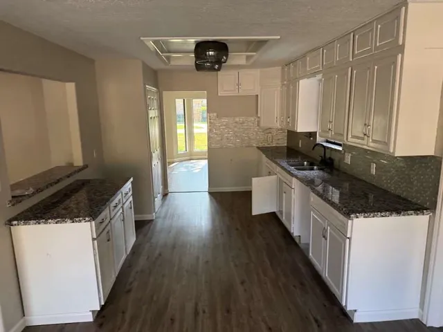 a kitchen with granite countertop a sink and wooden floor