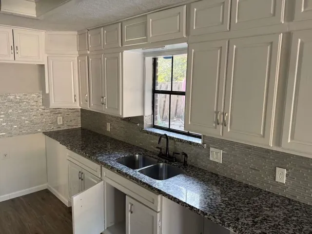 a kitchen with granite countertop a sink stainless steel appliances and cabinets