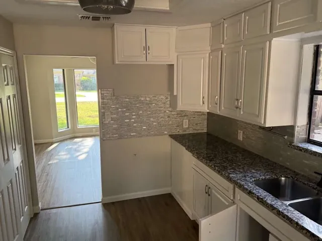 a kitchen with granite countertop a refrigerator sink and cabinets