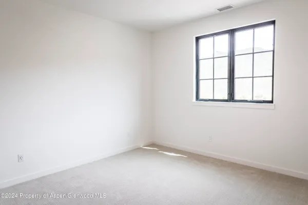 a view of an empty room with closet and mirror