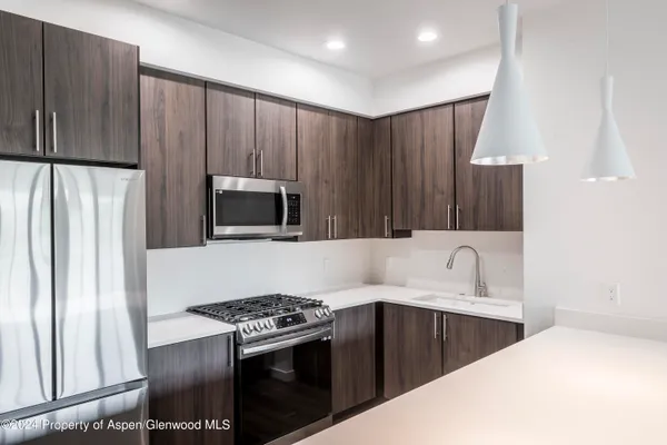 a kitchen with kitchen island a stove a sink and a refrigerator with wooden floor