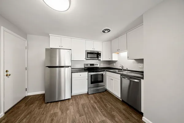 a kitchen with a refrigerator stove and white cabinets
