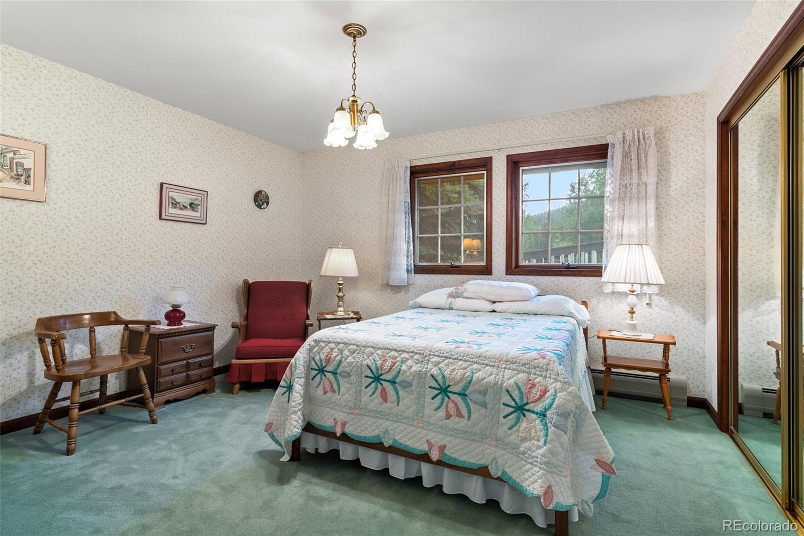 1680 Crow Valley Road Bailey, CO 80421 - Photo 32 of 50 a bedroom with a bed and a chandelier