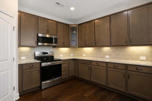 a kitchen with stainless steel appliances granite countertop a sink stove and microwave