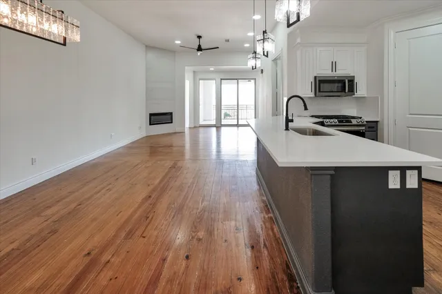 a large kitchen with a sink and wooden floor