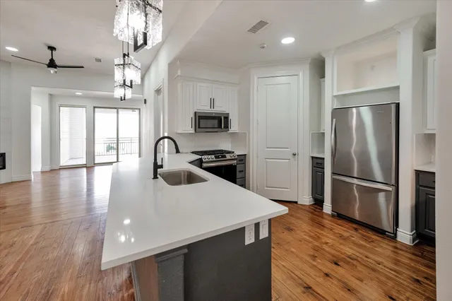 a kitchen with kitchen island a counter top space stainless steel appliances and wooden floor