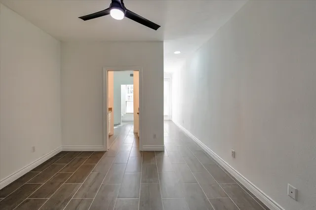 a view of a hallway with wooden floor and a chandelier fan