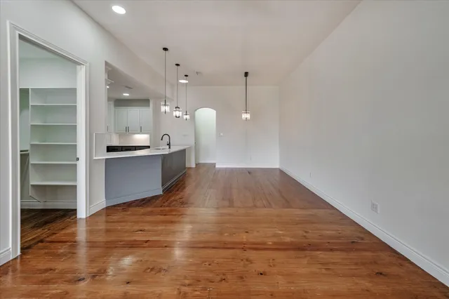 a view of kitchen and empty room with wooden floor