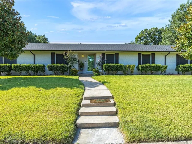 a front view of a house with a yard and potted plants
