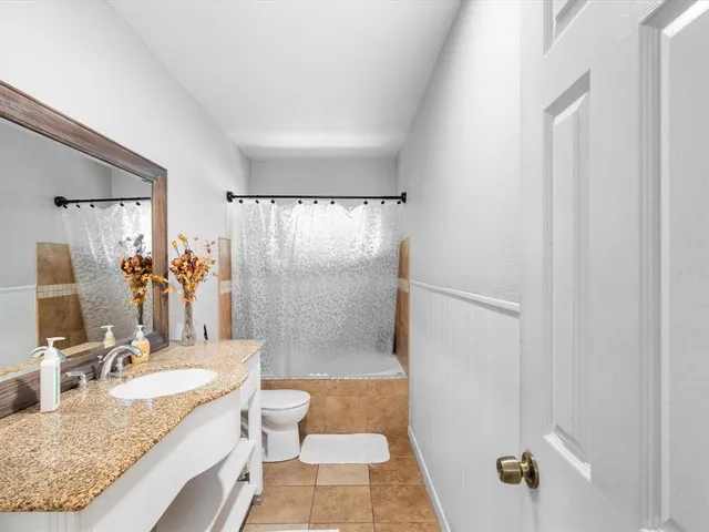 a bathroom with a granite countertop sink a toilet and shower