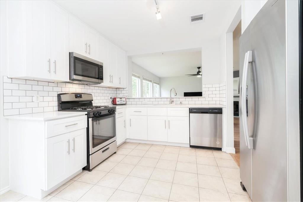 20805 Jumpers Delight Lane Pflugerville, TX 78660 - Photo 2 of 24 Kitchen featuring stainless steel appliances, white cabinets, decorative backsplash, ceiling fan, and light tile patterned floors