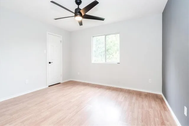an empty room with a window and a fan