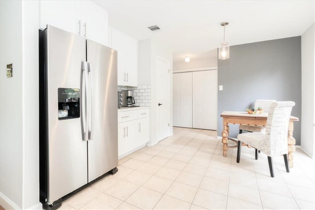 20805 Jumpers Delight Lane Pflugerville, TX 78660 - Photo 7 of 24 Kitchen with stainless steel refrigerator with ice dispenser, white cabinets, decorative backsplash, pendant lighting, and light countertops