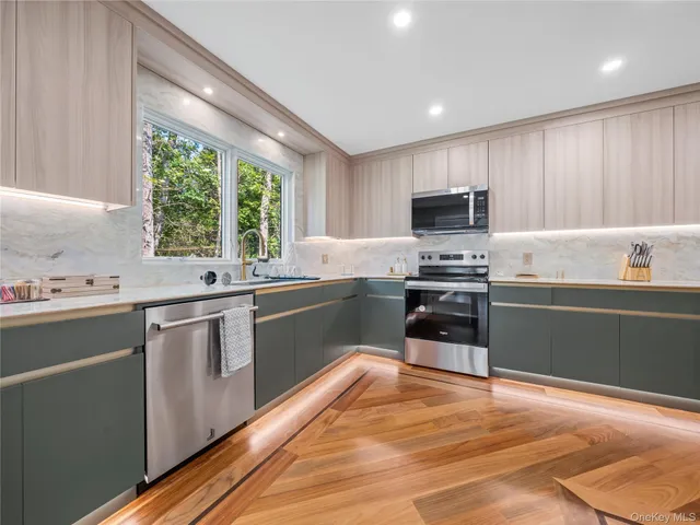 a kitchen with granite countertop a stove top oven a sink dishwasher a refrigerator and a oven with wooden floor