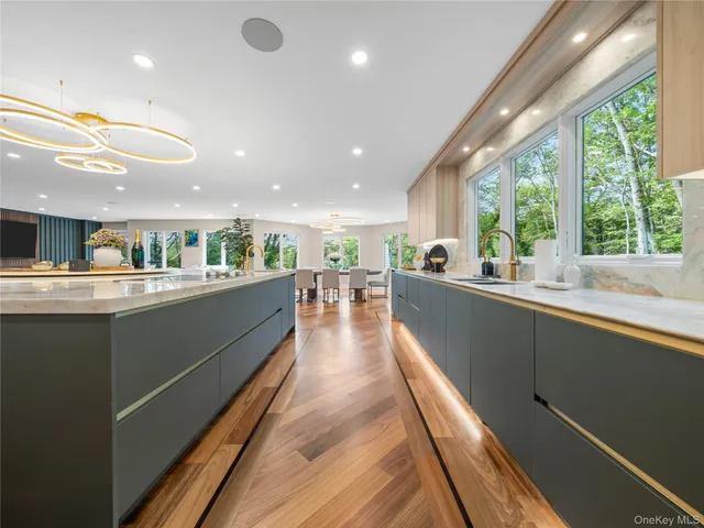 a view of a kitchen with kitchen island a large counter space a sink appliances and a large window