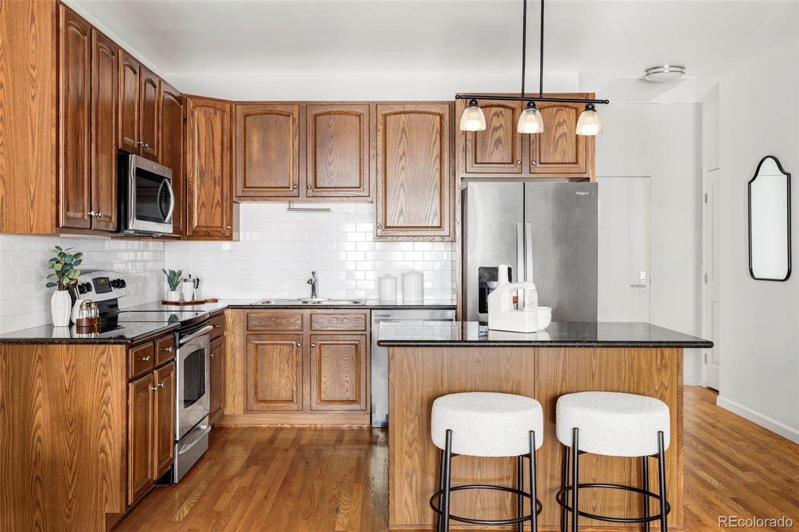 1950 Logan Street, Unit 1013 Denver, CO 80203 - Photo 3 of 23 a kitchen with stainless steel appliances granite countertop a stove top oven a sink a dining table and chairs with wooden floor
