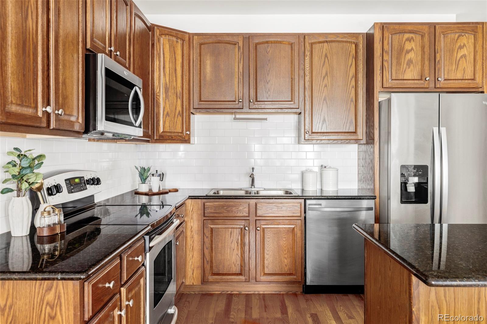 1950 Logan Street, Unit 1013 Denver, CO 80203 - Photo 5 of 23 a kitchen with stainless steel appliances granite countertop a refrigerator a stove a sink and a microwave