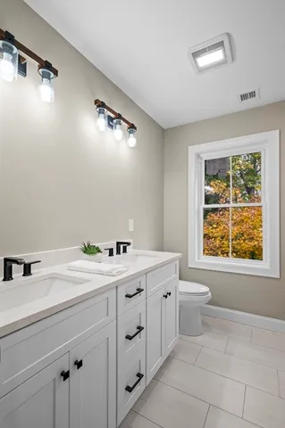 a bathroom with a granite countertop sink mirror vanity and toilet