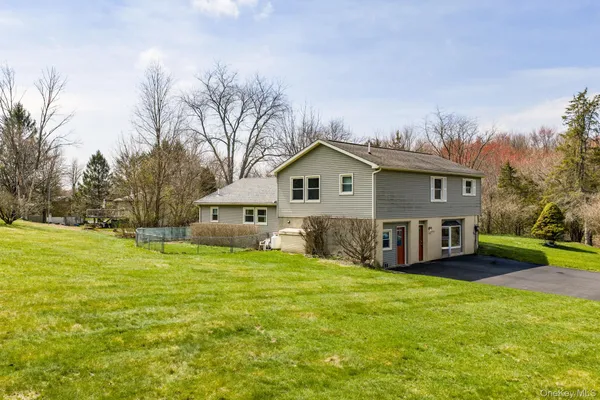 a view of a house with a big yard and large trees